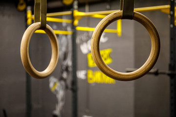 Gymnastic rings hanging at cross fitness gym. Closeup image of a crossfit dip rings in gym interior.