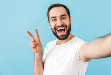 Cheerful man take a selfie by camera showing peace gesture.