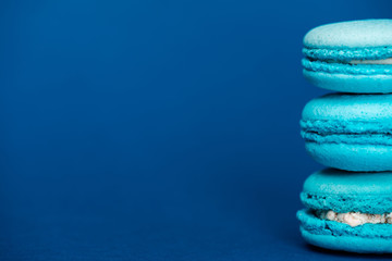 Fototapeta na wymiar sweet french macaroons on blue background with copy space