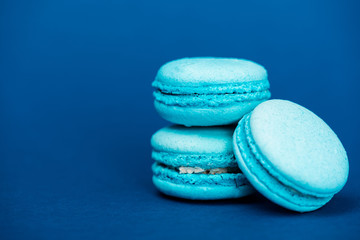 Fototapeta na wymiar tasty french macaroons on blue background with copy space