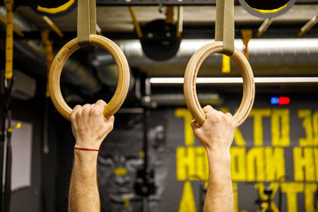 Young athlete with gymnastic dip rings in the gym. Focus on crossfit rings.