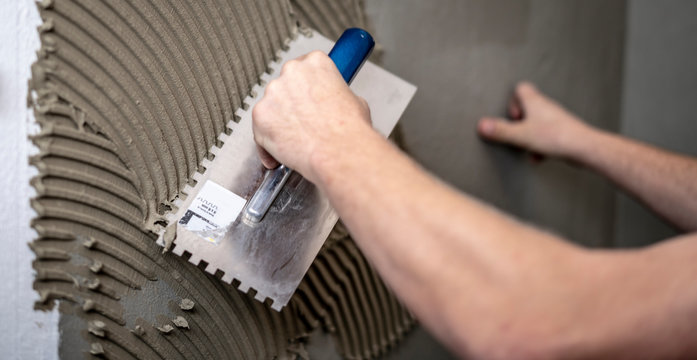 Fliesenleger zieht den Fliesenkleber an der Wand auf