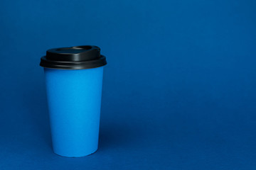 paper cups with coffee on classic blue background with copy space