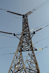 Pylon of an overhead power line against a clear blue sky.