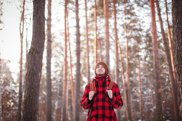 Male tourist with backpack walks on snow pine forest. Guy hiking at nature. Concept of winter holiday or vacation..