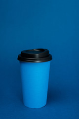 paper cups with coffee on classic blue background with copy space