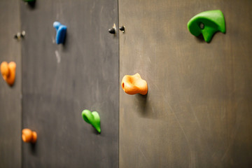 Grey climbing wall with colorful rocks.