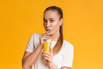 Cute Young Lady Drinking Orange Juice From Glass With Straw
