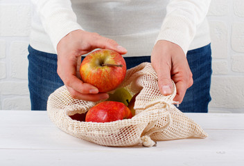 Woman puts organic apples in a textile bag