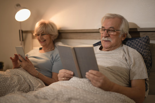 Smiling senior man and his wife resting in bedroom at night.