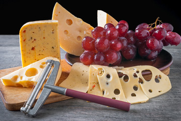 Still life of cream cheese with a bunch of grapes on a black background.
