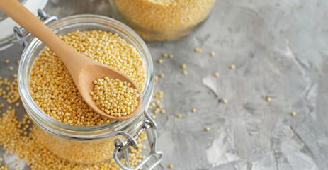 Raw dry hulled millet in a glass jar with a spoon
