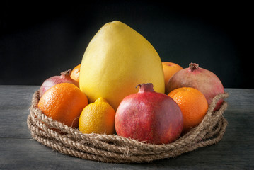 Still life of different fruits surrounded by a decorative rope.