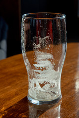 Empty beer glass standing on a table at the pub, lit by the sun from the window.
