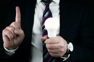 Man holds a light bulb.  businessman holding illuminated light bulb, idea, innovation and inspiration concept