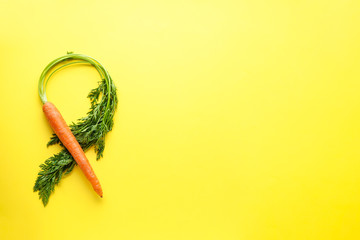 Flat lay composition with ripe fresh carrot on yellow background with space for text.