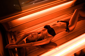 Beautiful young woman tanning skin treatment in modern solarium