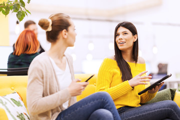 Two beautiful young female business colleagues having a chat in a modern office. Successfull...