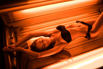 Beautiful young woman tanning skin treatment in modern solarium