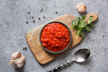 Tasty ajvar. Vegetable sauce or caviar of baked red bell pepper on grey. Balkan cuisine.