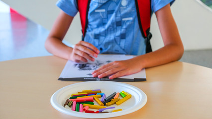 Boy draws with colored wax crayons