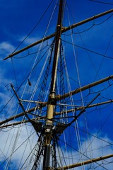  historic mast of the sailing ship ship with ropes against the blue sky