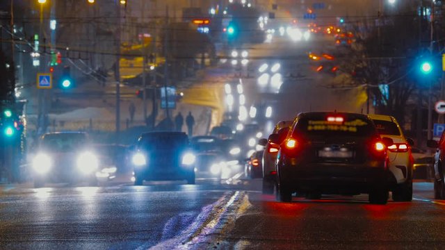 Timelapse of busy city traffic at night. Road illuminated by headlights and taillights of moving cars, glowing glare bokeh background. Transport flow movement.