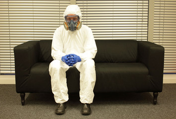 Quarantine. Professional in protective clothing, mask and gloves, sitting on the sofa  and waiting for the end