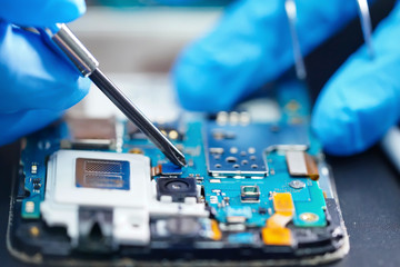 Technician repairing micro circuit main board of smartphone electronic technology : computer,...
