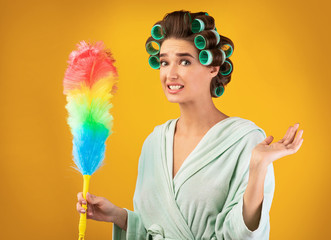 Confused Housewife With Curlers Holding Feather Duster, Studio Shot