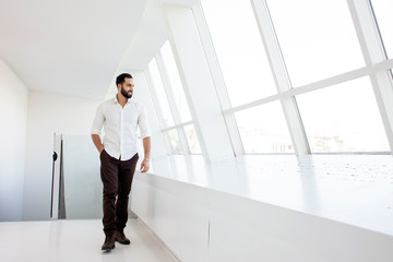 Fototapeta na wymiar Portrait of a successful handsome man in a white shirt in the morning in a white building, businessman looks out the window