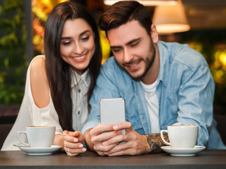 Boyfriend And Girlfriend Using Smartphone Sitting In Cafeteria