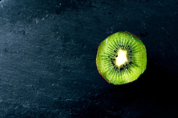 Half fresh kiwi on slate board.