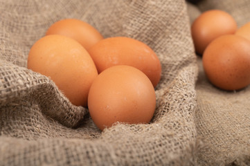A few chicken eggs on a background of rough homespun fabric. Country food. Close up.
