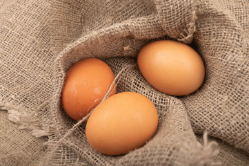 A few chicken eggs on a background of rough homespun fabric. Country food. Close up.