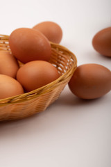 Chicken eggs in a wicker basket and scattered on a white background. Close up.