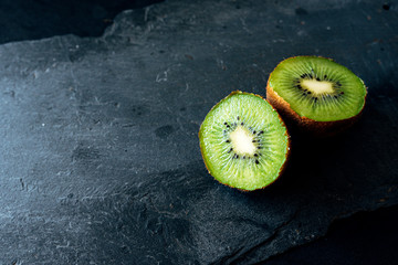 Fresh kiwi match in two halves on slate board. natural light. healthy food concept