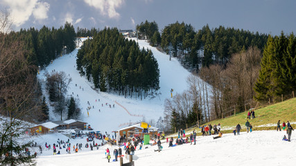 Families travel to the Sauerland in winter. They do winter sports on the ski slopes.