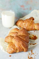Fresh french croissant with a glass of warm milk and honey for breakfast. Homemade French Croissants on a Background. Ruddy crust and vanilla flavor of freshly baked treats. Homemade pastry concept.