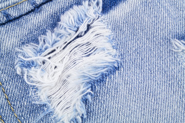 Blue denim jeans textile with hole close up