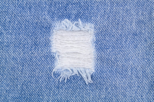 Blue denim jeans textile with hole close up