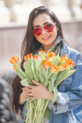 Young attractive woman outdoors. Pretty female holding flowers. Lady with tulips.