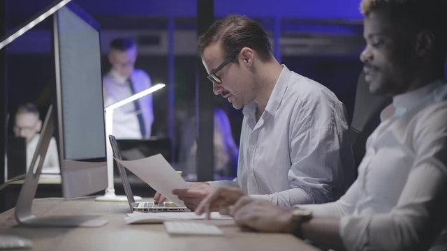 Businessmen working hard late together on computer and laptop in office