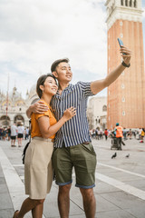 Loving couple in Venice, Italy - Millennials take a selfie in Piazza San Marco - Asian young people on vacation in Italy