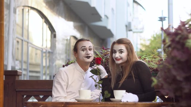 Two happy mime on a date in the street cafe. Romantic date