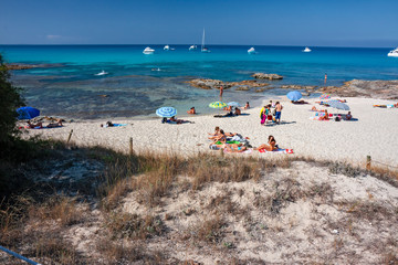 Fototapeta na wymiar Bathers sunbathing in the wild and sunny beaches of Formentera in the Balearic islands of Spain.