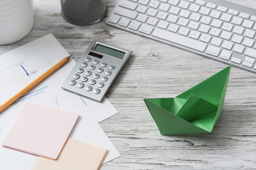 Top view office workspace with green paper ship