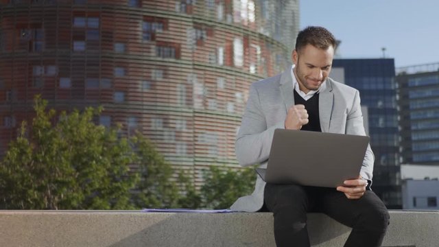 Businessman reading good news on laptop at street. Employee working on laptop