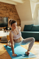 Young athletic woman stretching while exercising at home.