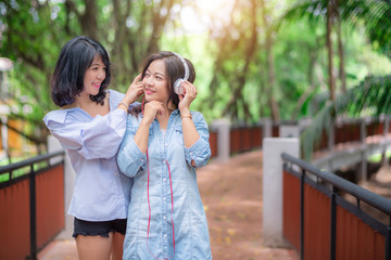 Young carefree attractive Asian women enjoy to listening music in garden, happiness and cheerful friendship concept.